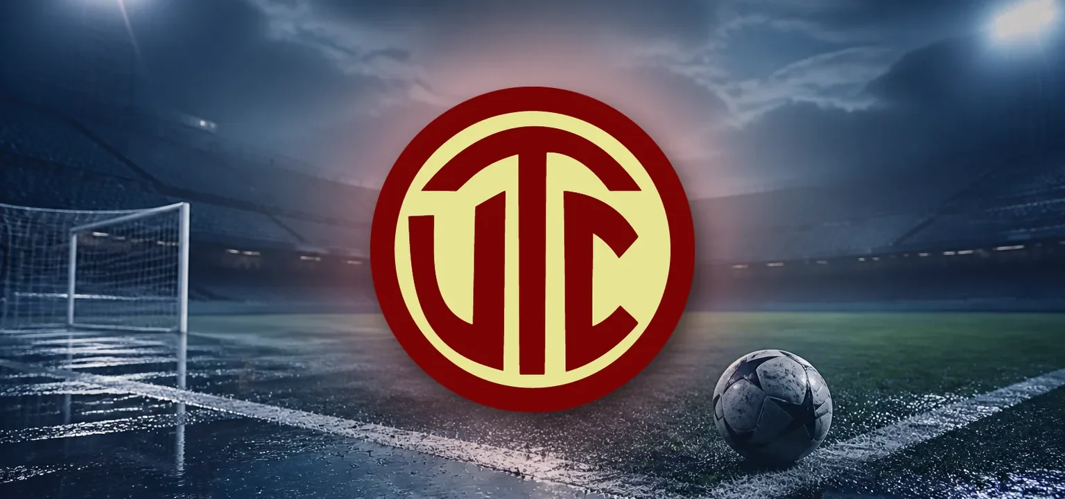 Escudo de UTC de Cajamarca sobre un estadio vacío y mojado al anochecer